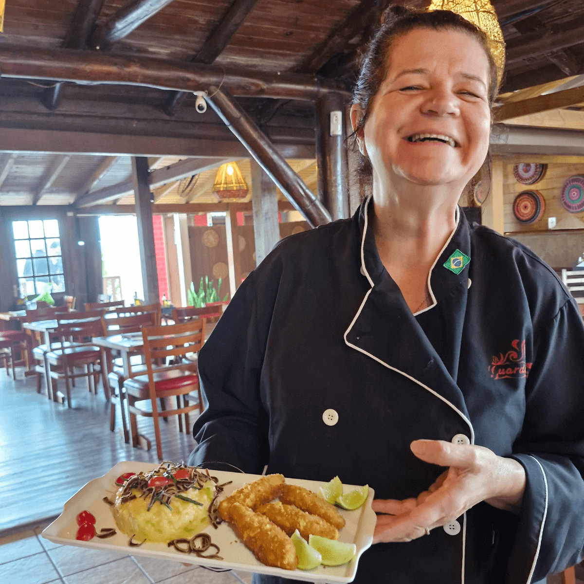 Chef Telma no salão do GuardaGosto com prato de entrada.